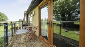 Ein Zimmer mit einer Schiebetür, einem kleinen Tisch mit Stühlen und Blick auf eine Grünfläche.