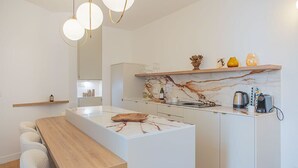 Eine moderne Küche mit Marmorfliesenspiegel, einer Holzinsel und Pendelleuchten.
