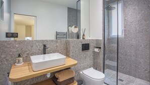 Ein modernes Badezimmer mit einem rechteckigen Waschbecken, einer Toilette und einer Duschkabine.