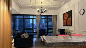 A modern living room with a dark sofa, a marble coffee table, and a city view through large windows. - Modern Studio with Stunning City Views (Kuala Lumpur)