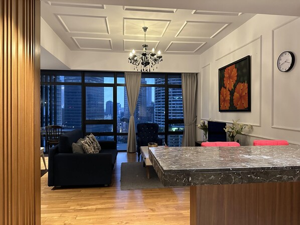A modern living room with a dark sofa, a marble coffee table, and a city view through large windows.