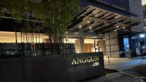 A building entrance with a sign reading "ANGGUN JSI" and a stone wall with plants. - Modern Studio with Stunning City Views (Kuala Lumpur)