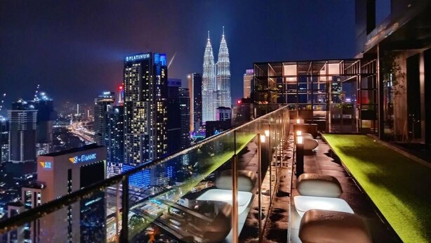 A rooftop bar with a city view, including the Petronas Towers, and a glass railing overlooking the cityscape. - Modern Studio with Stunning City Views (Kuala Lumpur)