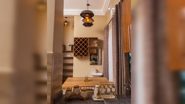 A narrow hallway with a wooden table, a wine rack, and a hanging light fixture. - Beautiful 1-Bed apartment in the heart of Kampala (Kampala)