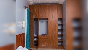 A walk-in closet with wooden cabinets, a hanging rod, and a built-in shelf unit. - Beautiful 1-Bed apartment in the heart of Kampala (Kampala)