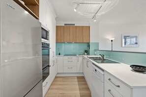 A modern kitchen with white cabinetry, a built-in oven, and a countertop with a sink.