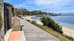 A coastal walkway with a wooden deck, a sandy beach, and a calm sea. - La Porta Sul Mare in Golfo Aranci (Golfo Aranci)