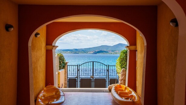 An arched doorway leading to a balcony with a view of a body of water and distant hills. - La Porta Sul Mare in Golfo Aranci (Golfo Aranci)