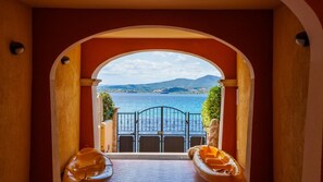 An arched doorway leading to a balcony with a view of a body of water and distant hills. - La Porta Sul Mare in Golfo Aranci (Golfo Aranci)