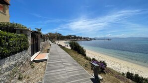 A coastal walkway leading to a beach with a clear view of the sea and distant mountains. - La Porta Sul Mare in Golfo Aranci (Golfo Aranci)