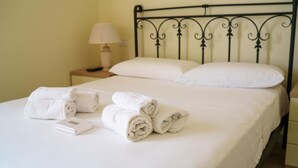 A neatly made bed with rolled white towels and a white box, a bedside lamp, and a metal headboard. - La Porta Sul Mare in Golfo Aranci (Golfo Aranci)