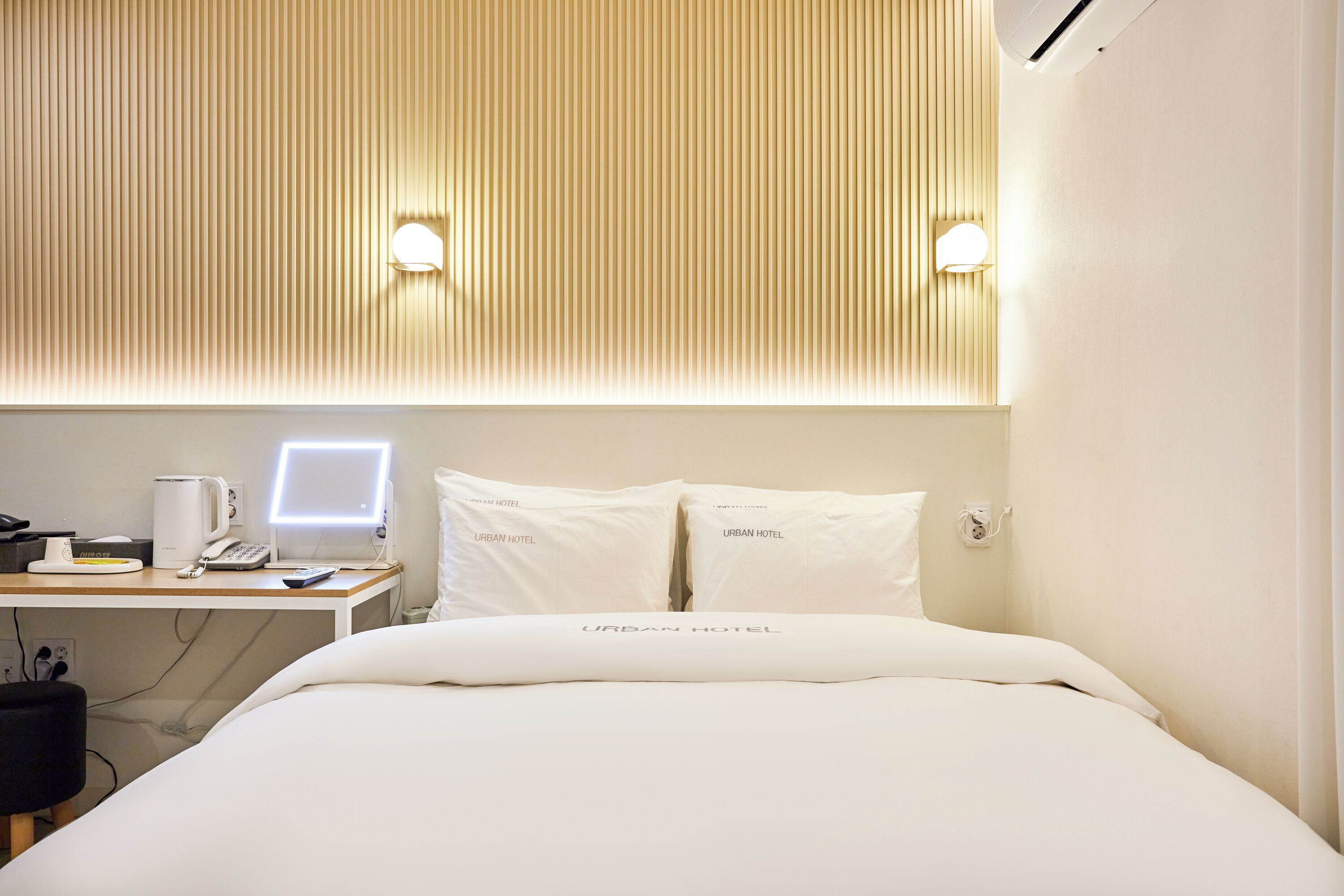 Habitació d'hotel amb un llit, una taula de treball amb un ordinador i dues làmpades de nit.