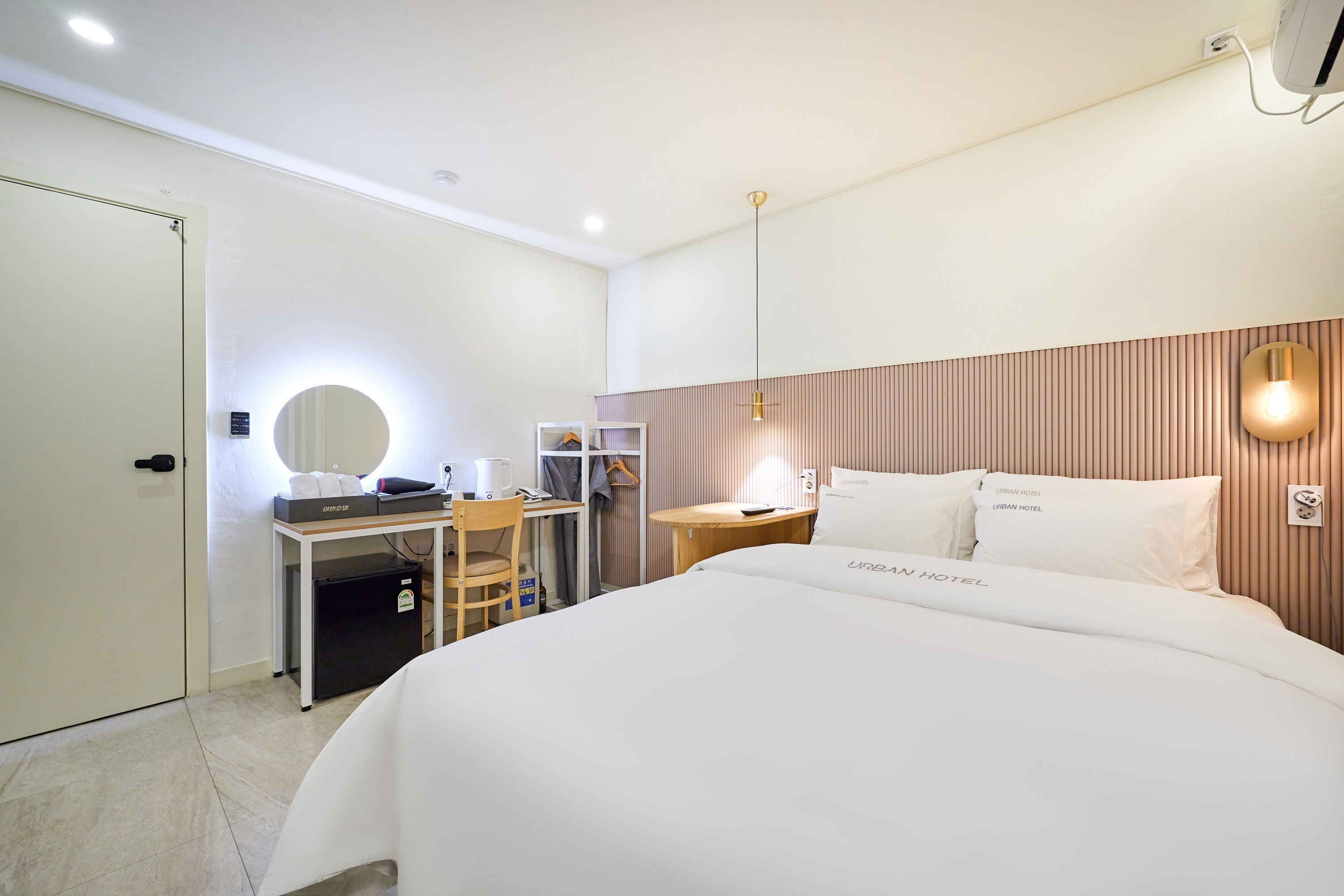 A hotel room with a bed, desk, chair, and a mirror.
