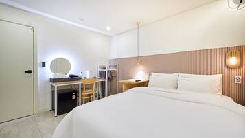 A hotel room with a bed, desk, chair, and a mirror.