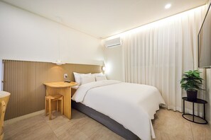 Una habitación de hotel moderna con cama, mesita de noche, lámpara y una planta en maceta.