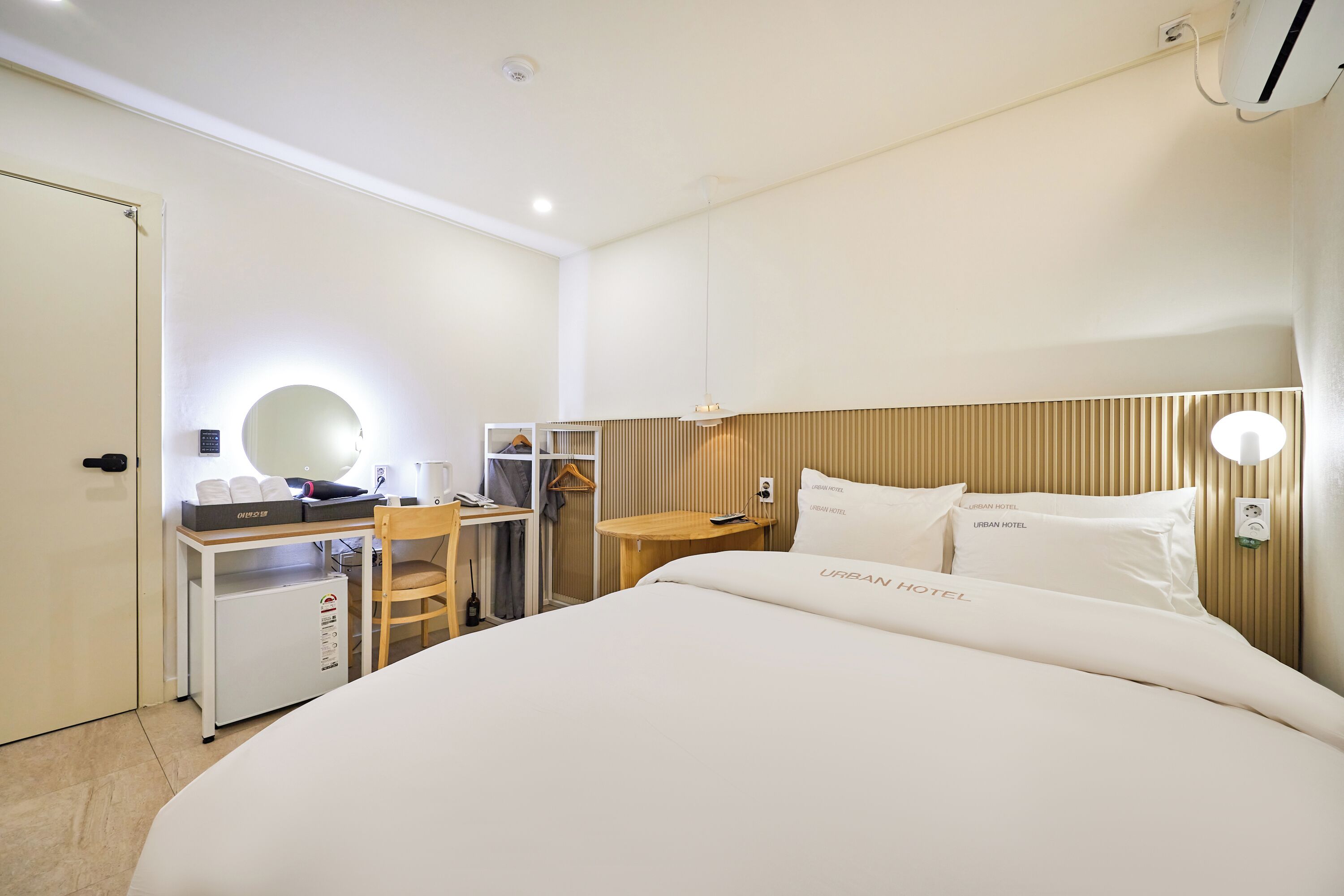 Una habitación de hotel con cama, escritorio, silla y un refrigerador pequeño.