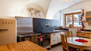 Una cucina con frigorifero in acciaio inox, un piano di lavoro nero, un tavolo da pranzo in legno e una finestra con vista all'esterno.