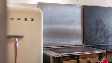 A kitchen with a stainless steel range hood, a white refrigerator with 'SMEG' on it, and a world map on the wall.