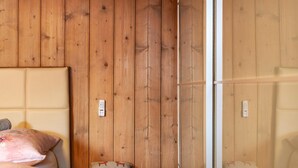 Una stanza con pareti in legno a pannelli, un letto con testiera e una panca.