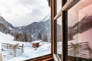 A snowy mountain landscape with a wooden cabin and a horse pen visible through a window. - Holiday home 'Liberty Ranch Marlstein' with mountain view and WiFi (Oetz)