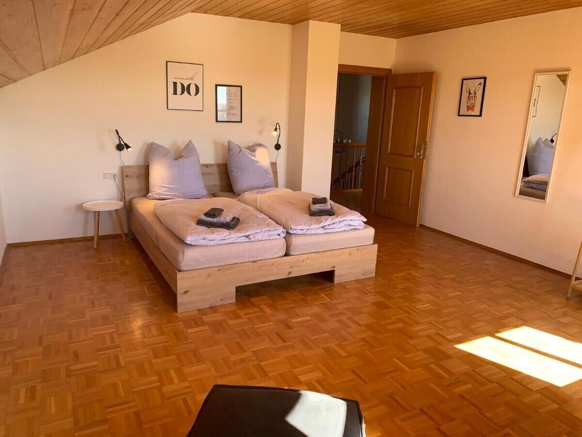 Une chambre à coucher avec un lit en bois, une petite table de chevet et un miroir.