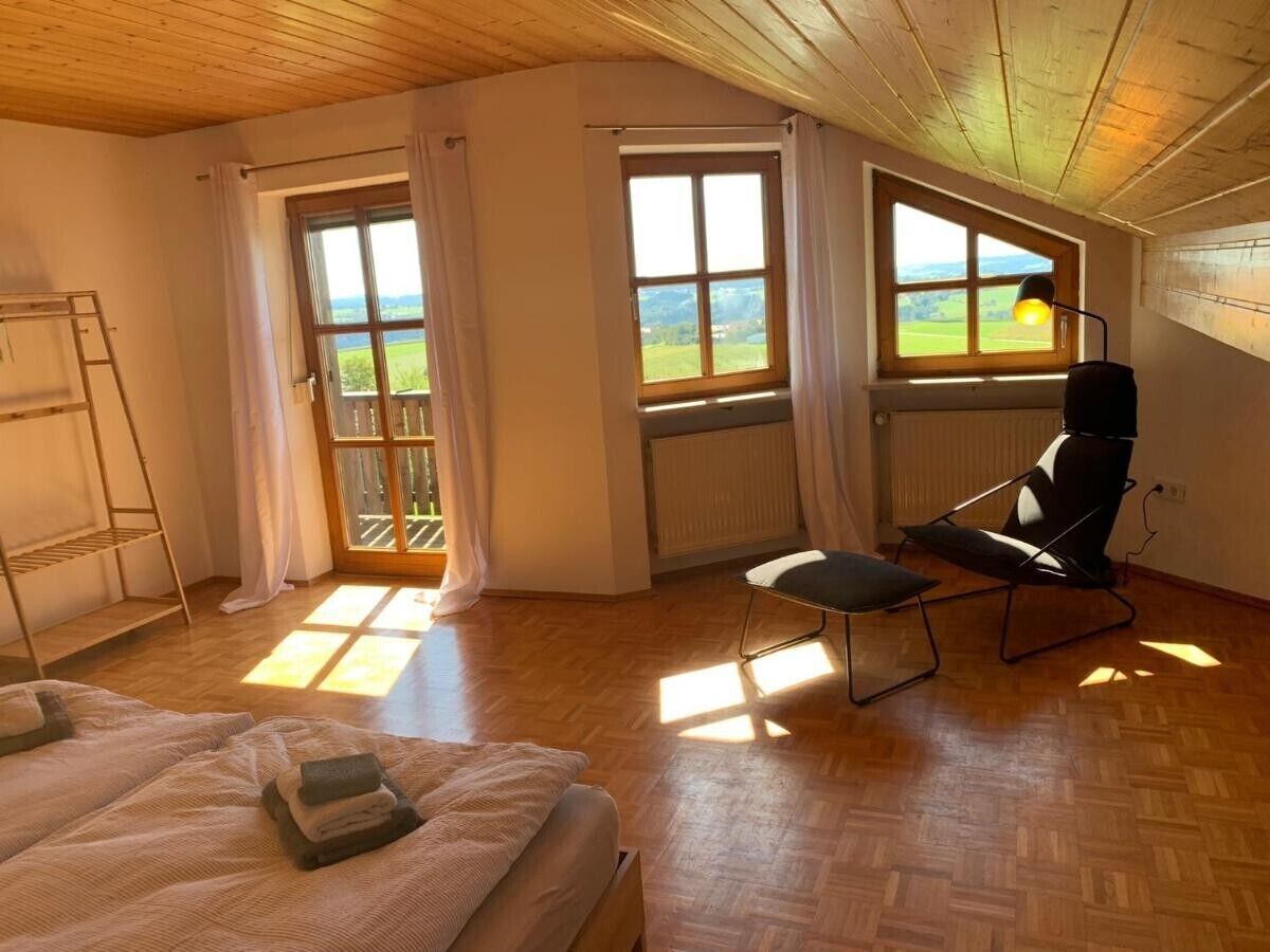 A room with a bed, a chair, a radiator, and a window with a view of the outdoors.