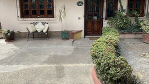 Una casa con techo de tejas, dos puertas de madera y un banco con cojines en el exterior.