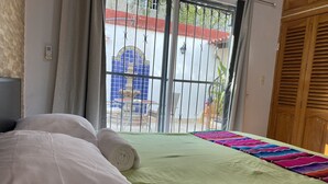 Habitación de hotel con cama, vistas al exterior y puerta de madera.