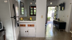 Una cocina con refrigerador de acero inoxidable, armarios blancos y piso de baldosas.