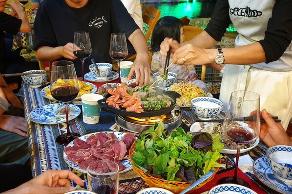 A dining table with various dishes, including meat, vegetables, and a hot plate.