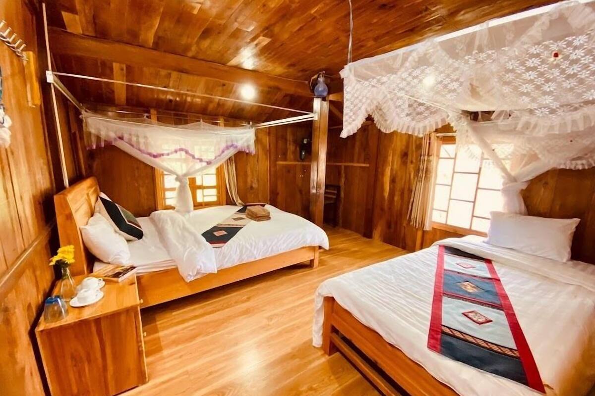 A wooden cabin bedroom with two beds, a wooden nightstand, and a hanging light fixture.