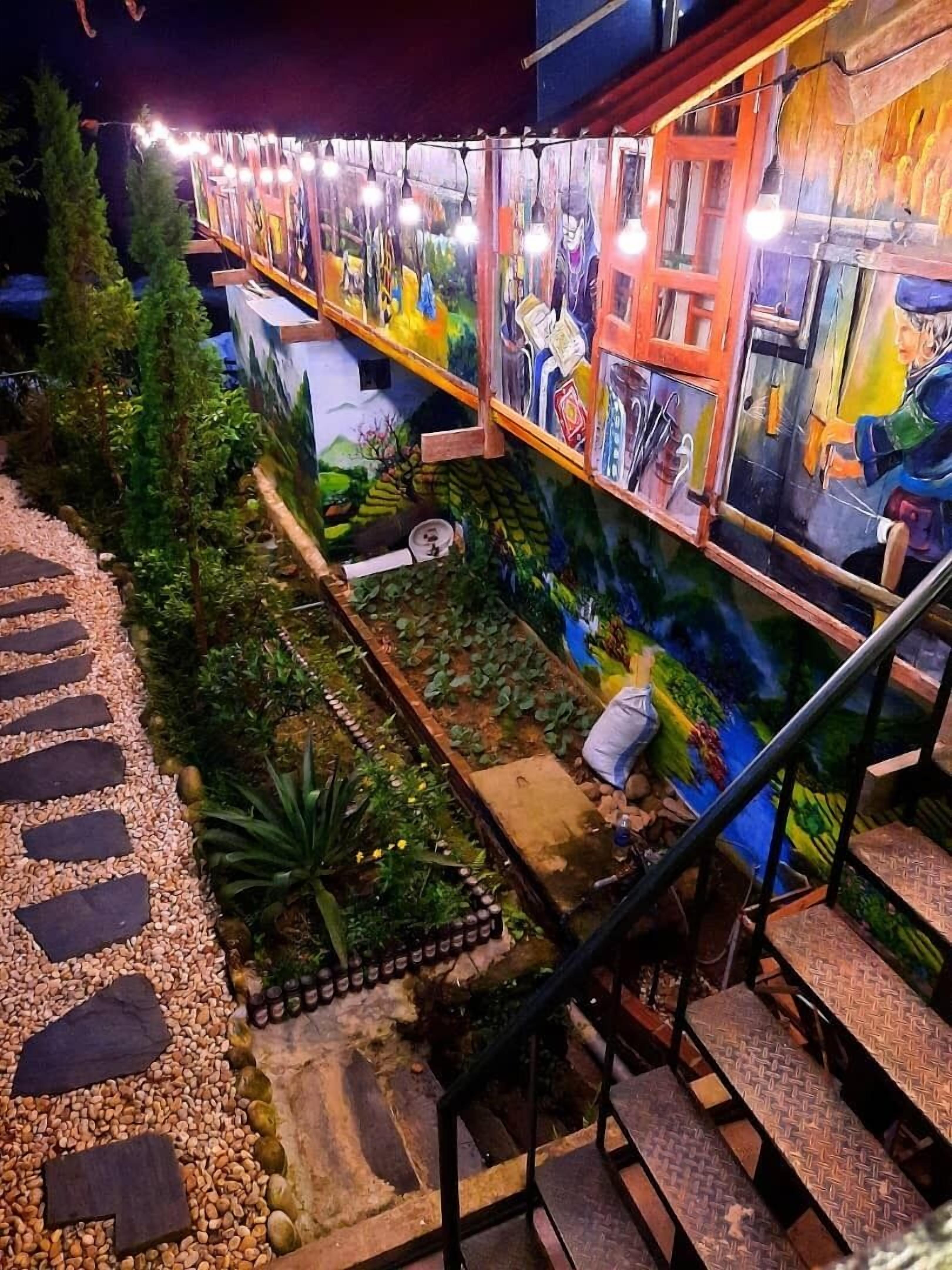 A multi-level outdoor area with a staircase, decorative plants, and a mural.