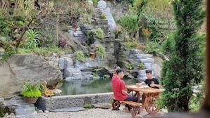 A garden with a pond, stone structures, and potted plants. - Peace Home (Ta Van)