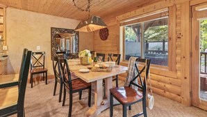 Un interior de madera con una mesa de comedor, sillas, una araña, un espejo y una ventana.