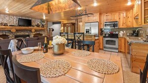 Interior de madera con una mesa de comedor, sillas, zona de cocina y chimenea.