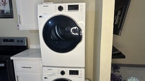 Een gestapelde wasmachine en droger combinatie met digitale bediening en een vochtsensor.