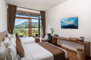 Habitación de hotel con dos camas, un escritorio, una silla, un televisor y vistas a un paisaje montañoso.