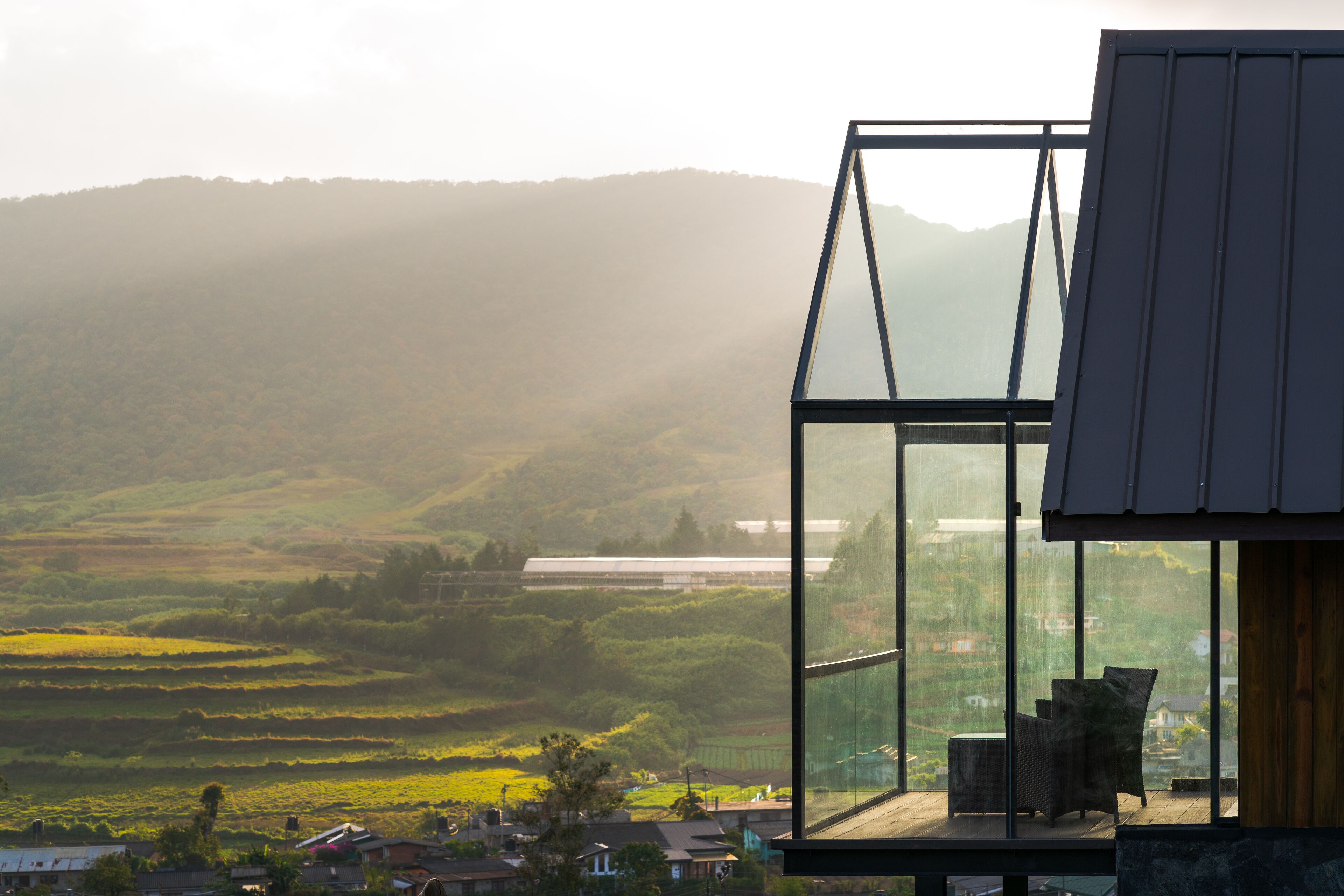 Ein modernes Gebäude aus Glas mit Blick auf eine hügelige Landschaft.