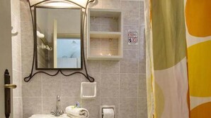 A bathroom with a pedestal sink, a toilet, a mirror, and a shower curtain.