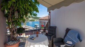 Un balcon avec une table, des chaises, un pot de fleurs et une vue sur la mer.