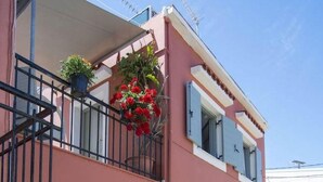 A two-story building with a balcony, potted plants, and a clear sky. - Dora II Studio - Simple Sweet Getaway (Paxos)