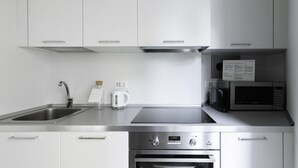 Une cuisine moderne équipée d’appareils électroménagers en acier inoxydable, notamment un four à micro-ondes, un four et une bouilloire.