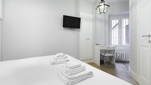 Une chambre d’hôtel avec un lit, un bureau, une chaise, une télévision et une fenêtre.