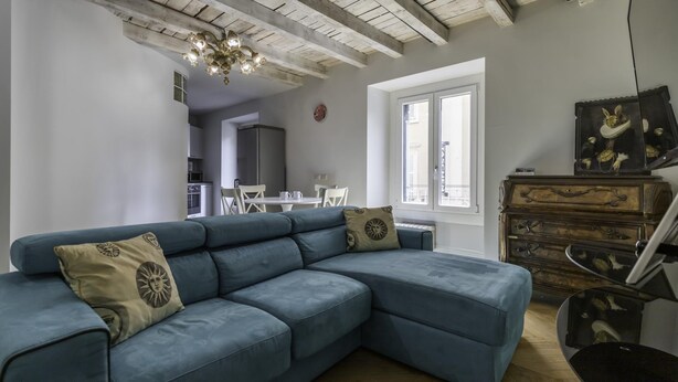 Un salon moderne avec un canapé d’angle bleu, une commode en bois et un lustre.