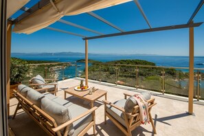 Un balcón con mesa, sillas y vista al mar y a las montañas.