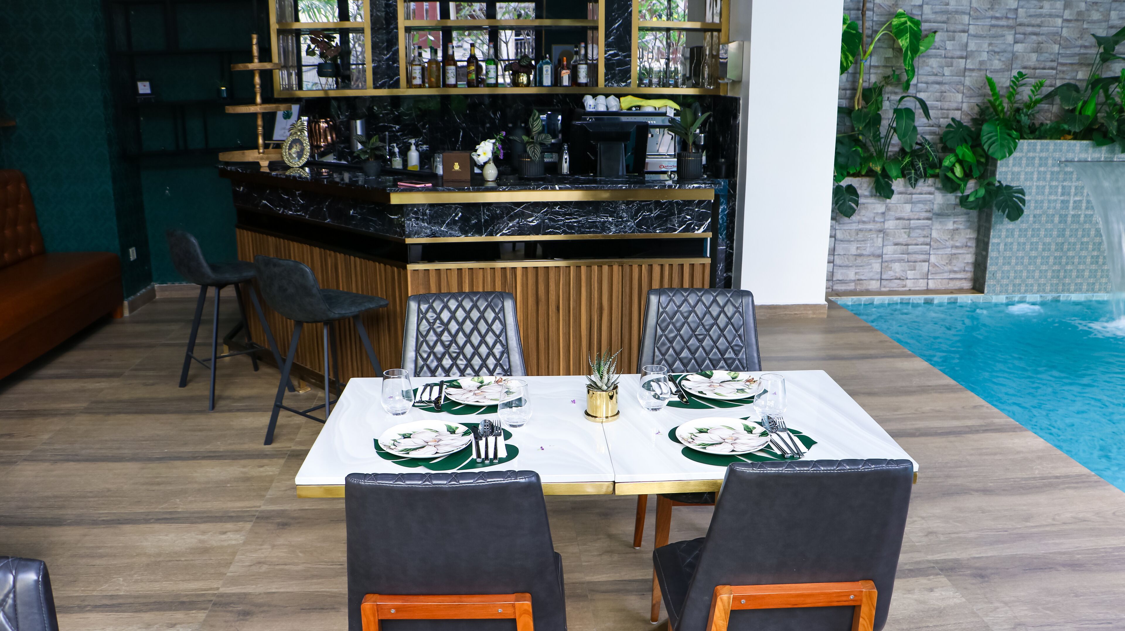 Een restaurant met uitzicht op het zwembad, een bar en een eetgedeelte met twee stoelen en een tafel gedekt voor twee personen.
