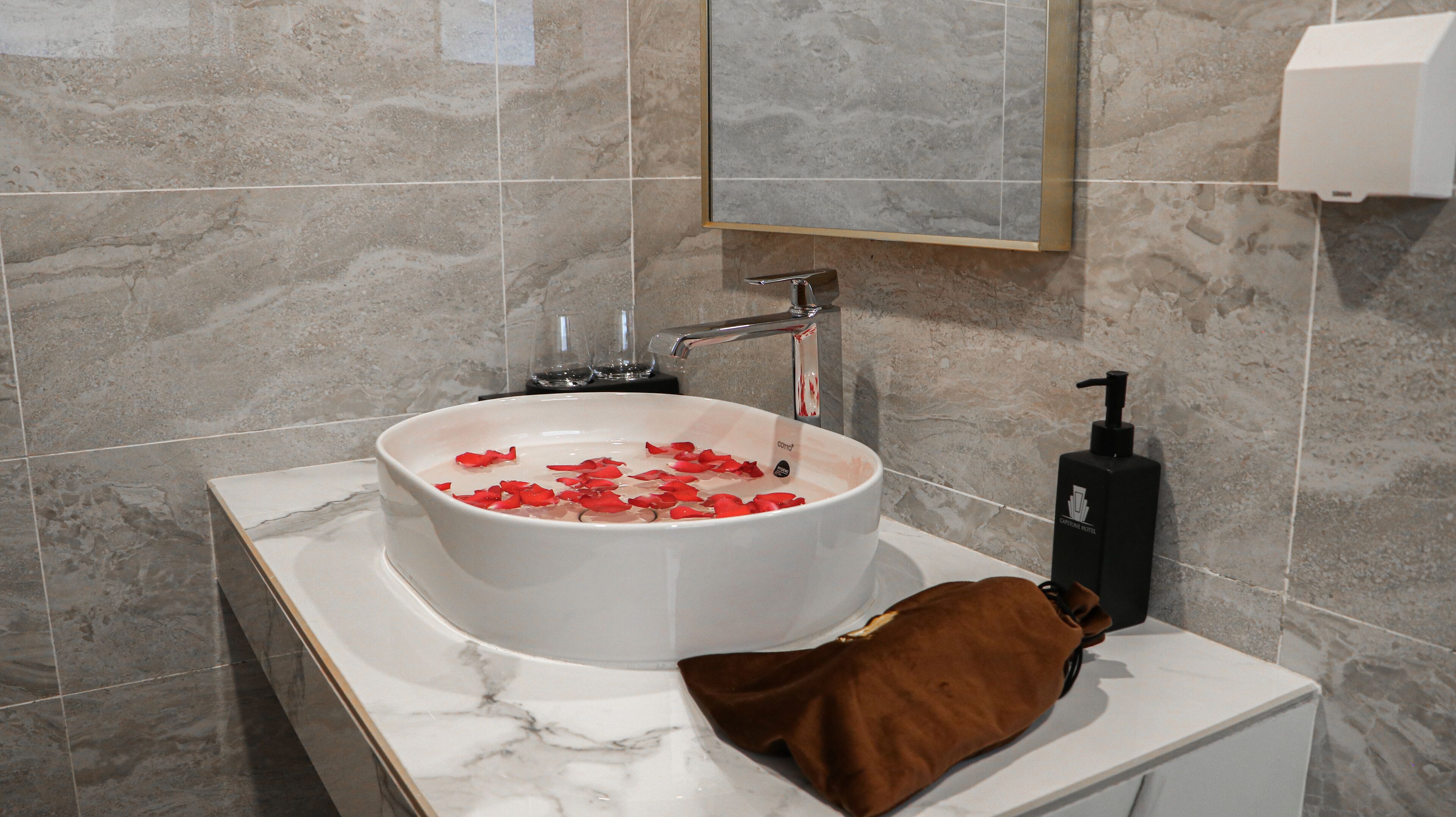 A bathroom with a marble sink, a mirror, and a towel rack.