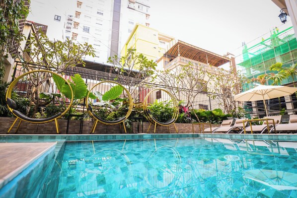 A swimming pool with lounge chairs and a decorative metal fence. - Mettavary Hotel (Phnom Penh)