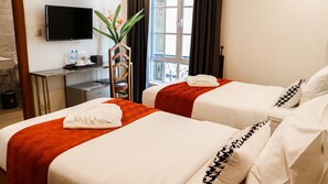 A hotel room with two beds, a TV, a desk with a computer, and a window with curtains. - Mettavary Hotel (Phnom Penh)