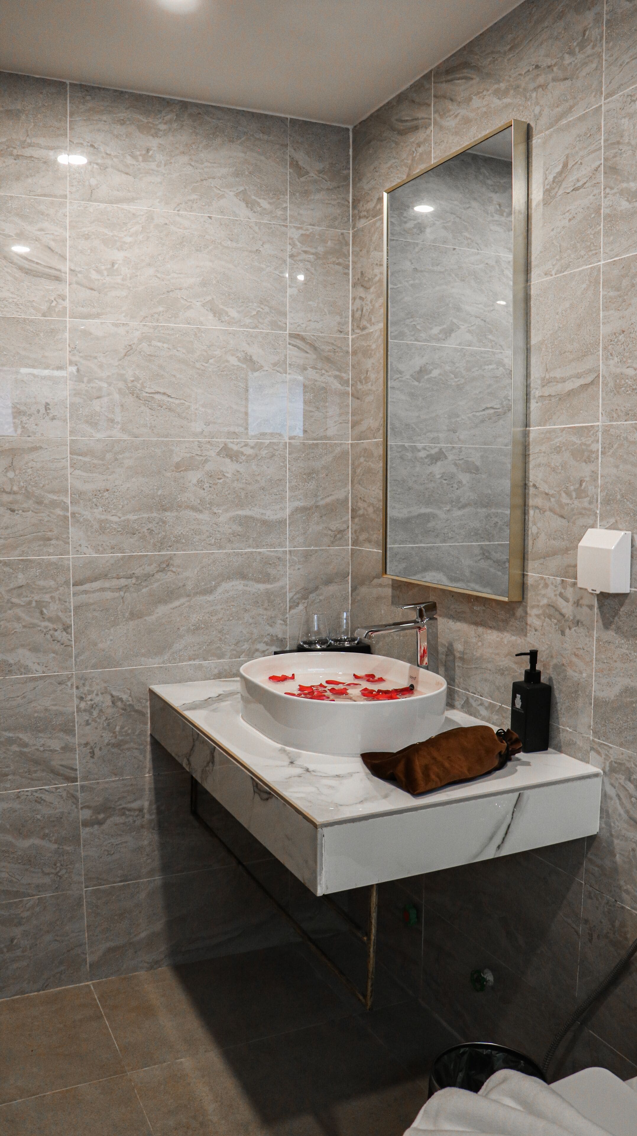 A bathroom with a marble sink, a mirror, and a towel rack.